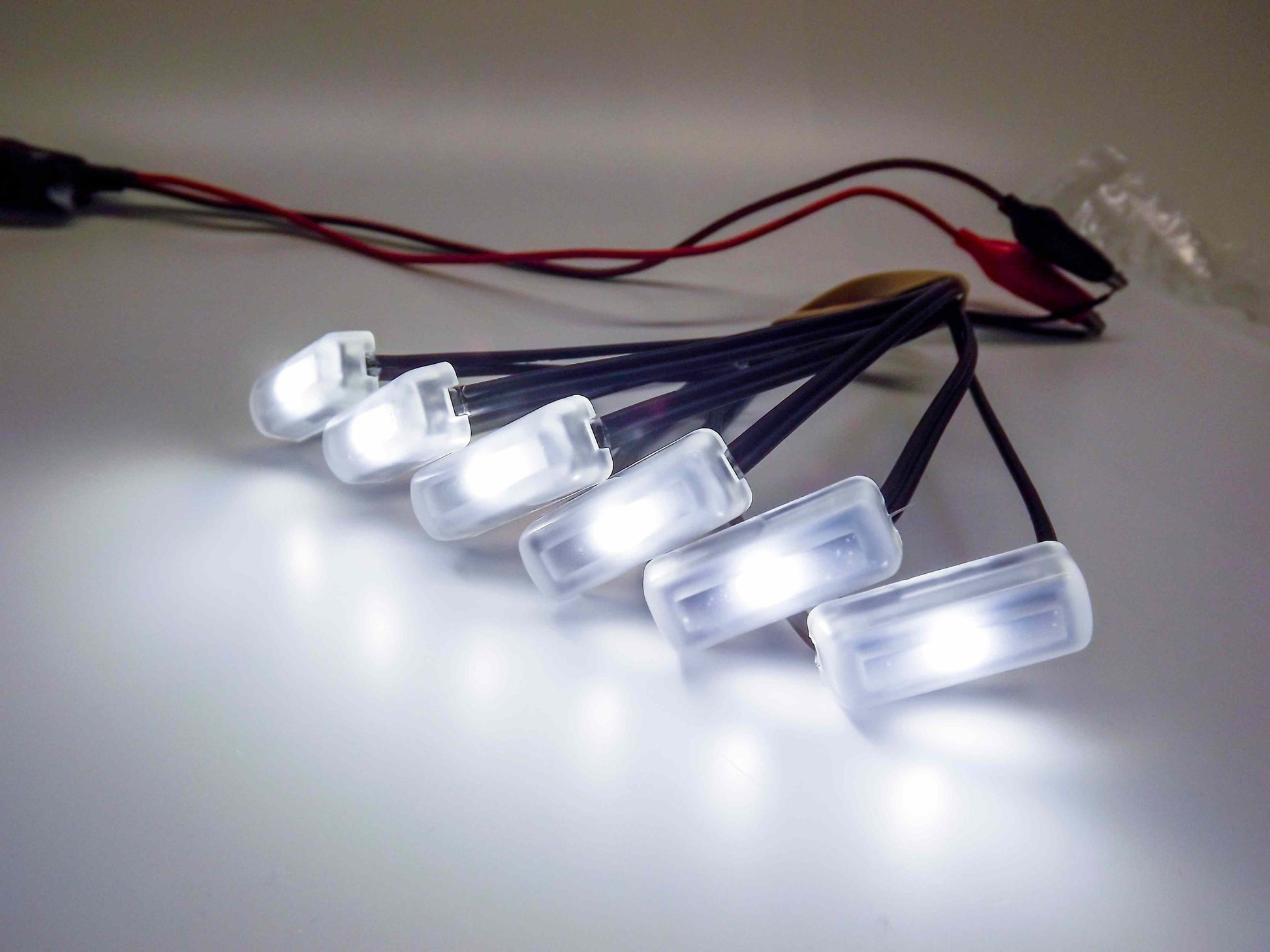 Row of small LED lights with wires on a light background