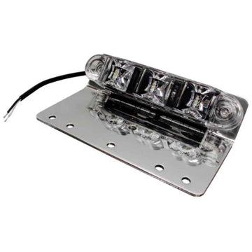 A silver TecNiq E10 ground/pump panel light featuring LED illumination, mounted on a flat surface with a wire attached.